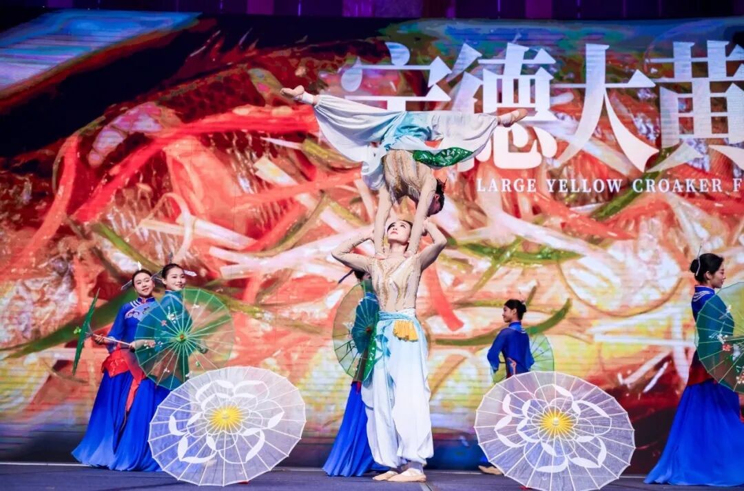 A dance performance set against a backdrop of large yellow croakers.