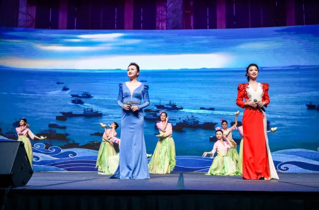 바다 풍경을 배경으로 노래하고 춤추는 공연자들.